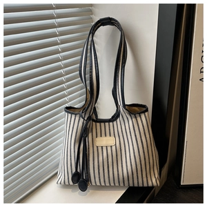 Detailed view of striped canvas tote bag with navy blue accents and dark leather trim