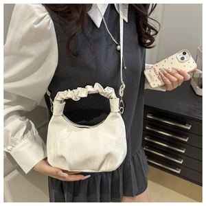 Detail of white pleated dumpling bag with ruched handle and leather texture finish