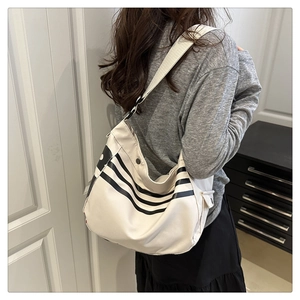 Détail du sac à bandoulière crème avec rayures noires et large sangle sur modèle