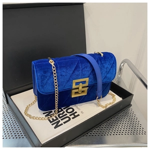 Macro detail of royal blue velvet crossbody bag with V-shaped quilting and gold hardware