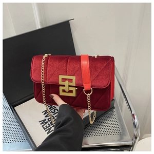Detail of dark red velvet crossbody bag with V-shaped quilting and gold metal chain strap
