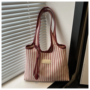 Detail of red striped canvas tote with leather trim leaning against white shutters