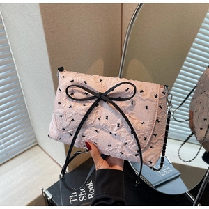 Close-up of pink pleated shoulder bag with floral patterns and a large black bow