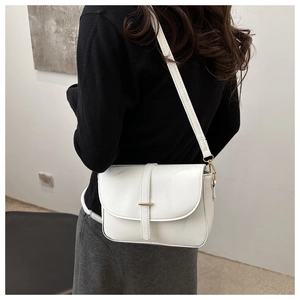 Detailed view of white glossy patent leather saddle bag with golden metallic trim