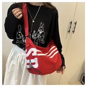 Détail du sac bandoulière en toile rouge avec lettres SUP blanches et trois bandes