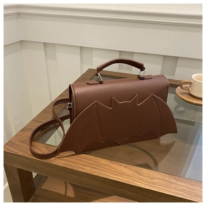 Detail view of the brown leather bat wing bag featuring top handle and adjustable strap