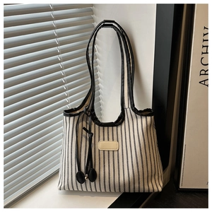 Detail of high-density striped canvas tote bag with black leather trim and tassel