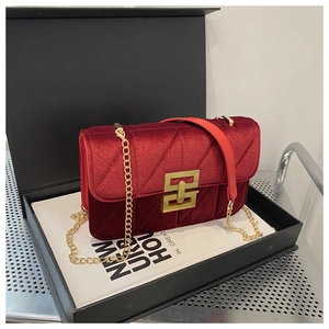 Detail of burgundy velvet quilted shoulder bag with gold metal buckle and chain strap