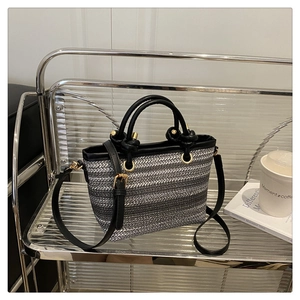 Detail of woven bucket bag featuring gray striped texture and black leather accents