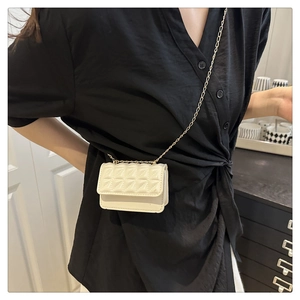 Close-up of off-white quilted mini bag with gold chain strap worn as waist accessory