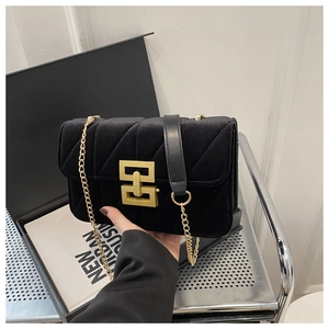 Detail of black velvet crossbody bag with gold chain strap and quilted fabric texture