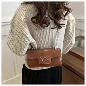 Detail of a brown PU leather crossbody bag with silver bow buckle and metal chain strap