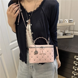 Pink quilted crossbody bag with silver studs and chain strap shown in a lifestyle setting