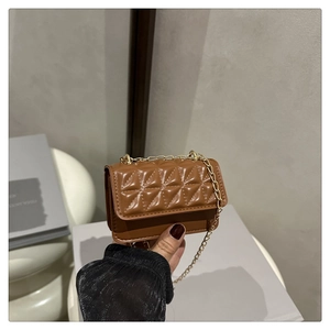 Close-up of caramel quilted mini bag with polished texture and golden chain strap
