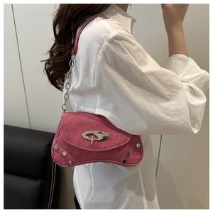 Detail of pink suede shoulder bag featuring silver rivets and a unique metal buckle