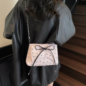 Pink crossbody bag with black bows on model in a stylish leather jacket look