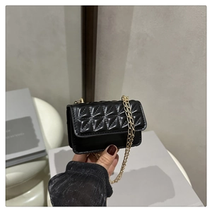 Detail of black mini crossbody bag with geometric quilting and golden chain strap