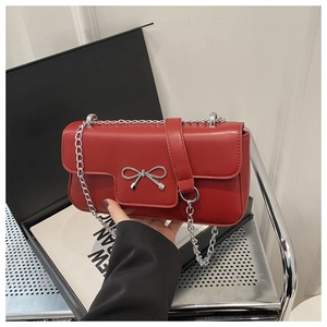 Detail of red square crossbody bag with silver bow ornament and chain strap