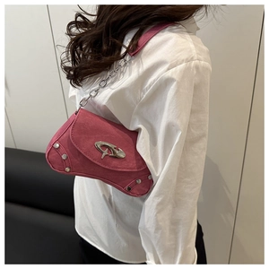 Detail of rose pink suede shoulder bag featuring a silver Y2K metal logo and studs