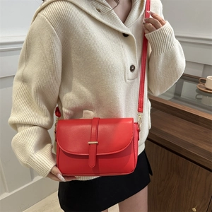 Bright red leather crossbody square bag with gold metal buckle on beige sweater model