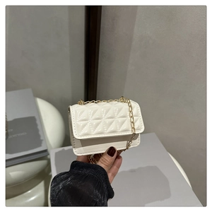 Close-up of cream quilted mini square bag with elegant gold chain shoulder strap