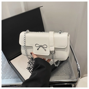 Detailed close-up of cream white chain bag with silver bow buckle and elegant metal strap