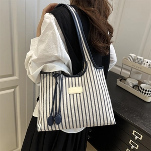 Sac fourre-tout minimaliste en toile à rayures bleues et blanches porté à l'épaule