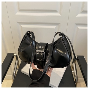 Close-up of black patent leather shoulder bag with silver eyelets and buckle detail