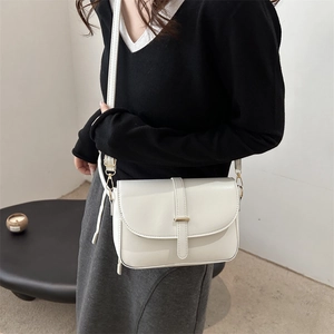 Minimalist white leather crossbody square bag with golden buckle shown as worn on shoulder