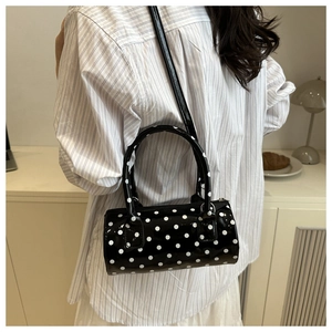 Vue détaillée arrière d'un sac cylindrique noir à pois en cuir verni brillant élégant