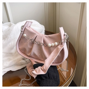 Detailed close-up of pink satin pleated shoulder bag with pearl chain and heart charms