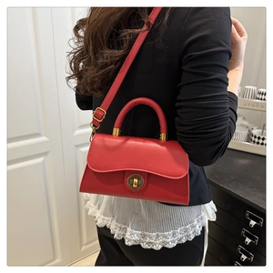 Model wearing a red leather crossbody bag with a wavy flap and gold hardware details