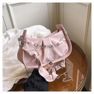 Détail du sac sous le bras plissé rose avec perles blanches et décoration de chaîne