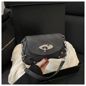 Detail of a vintage black Y2K shoulder bag with silver oval logo and metal rivets