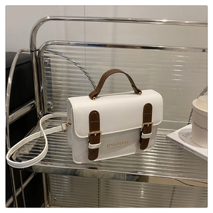 Detail of vintage white and brown crossbody bag showing buckle texture and brand logo