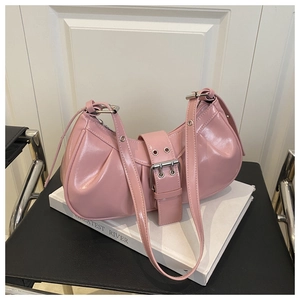 Detail of pink patent leather crescent bag with oversized buckle on a white book