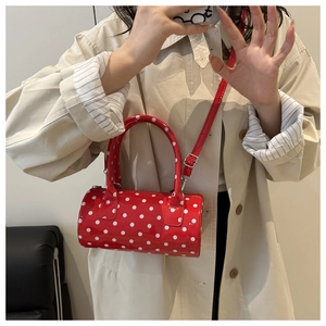 Detail of red barrel bag with white polka dots featuring glossy patent leather finish