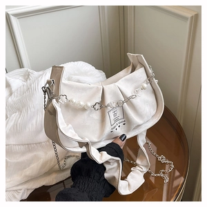 Détail du sac à bandoulière plissé blanc cassé avec chaîne en perles et écusson