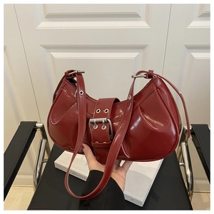 Detail of burgundy crescent bag in glossy patent leather with silver buckle and eyelets