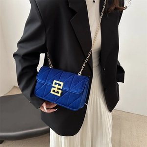 Royal blue velvet crossbody bag with quilted pattern and gold chain strap on model