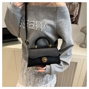 Chic black matte leather bag with vintage gold metal twist lock held by a model