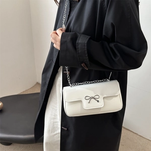 Minimalist white crossbody bag with silver bow hardware and metal chain strap for women