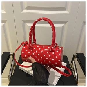 Close-up of red polka dot cylinder bag featuring patent leather and dual handles