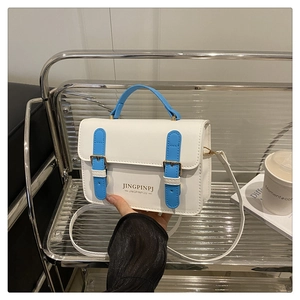 Detail of white PU leather mini bag with blue handles and gold buckle on a display rack