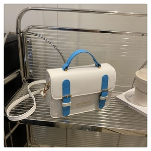Detailed view of the white and blue leather square bag with gold metal buckle and strap