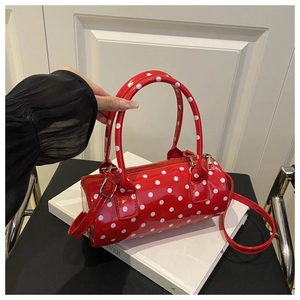 Close-up of a red polka dot patent leather cylinder bag with stylish top handles
