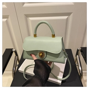 Close-up of mint green leather handbag with metal twist lock and detachable strap