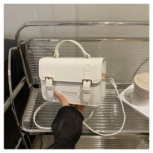 White faux leather rectangular bag with gold hardware on a modern silver rack