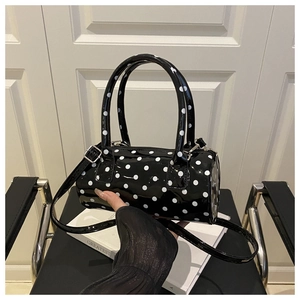 Detail of vintage black polka dot barrel bag with glossy patent leather finish