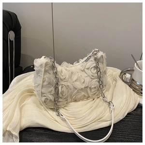 Nahaufnahme der cremeweißen Handtasche mit 3D-Stoffrosen und silberner Gliederkette